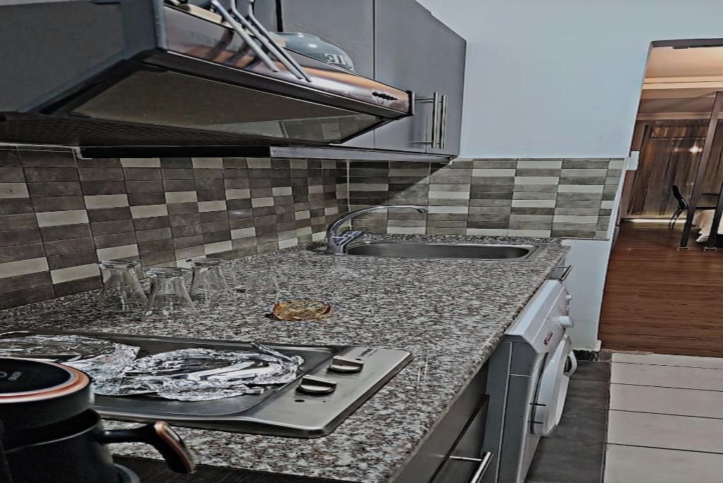 A kitchen with a granite countertop, stainless steel appliances, and a tiled backsplash.