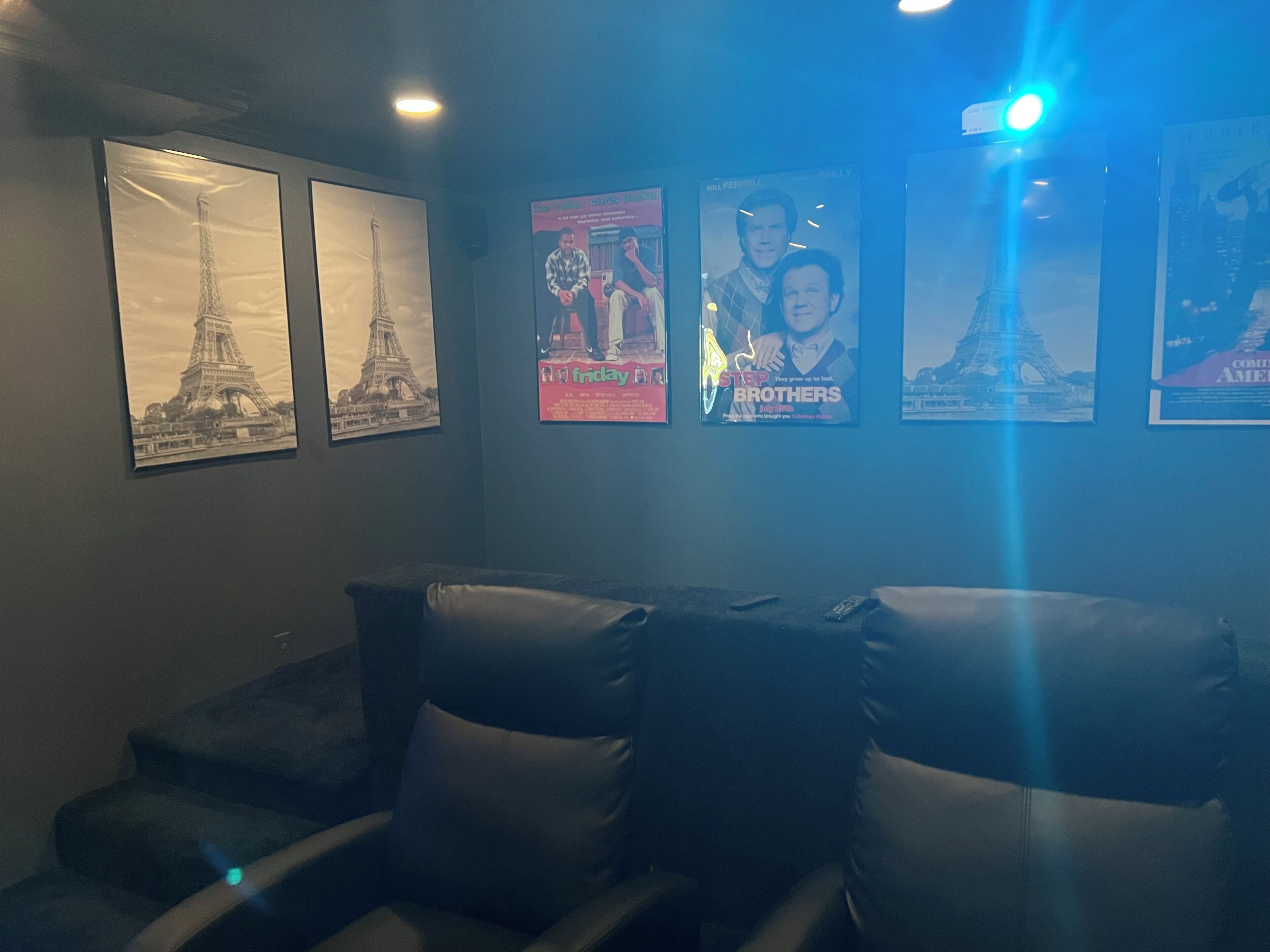 A room with a couch, pillows, and posters on the wall.