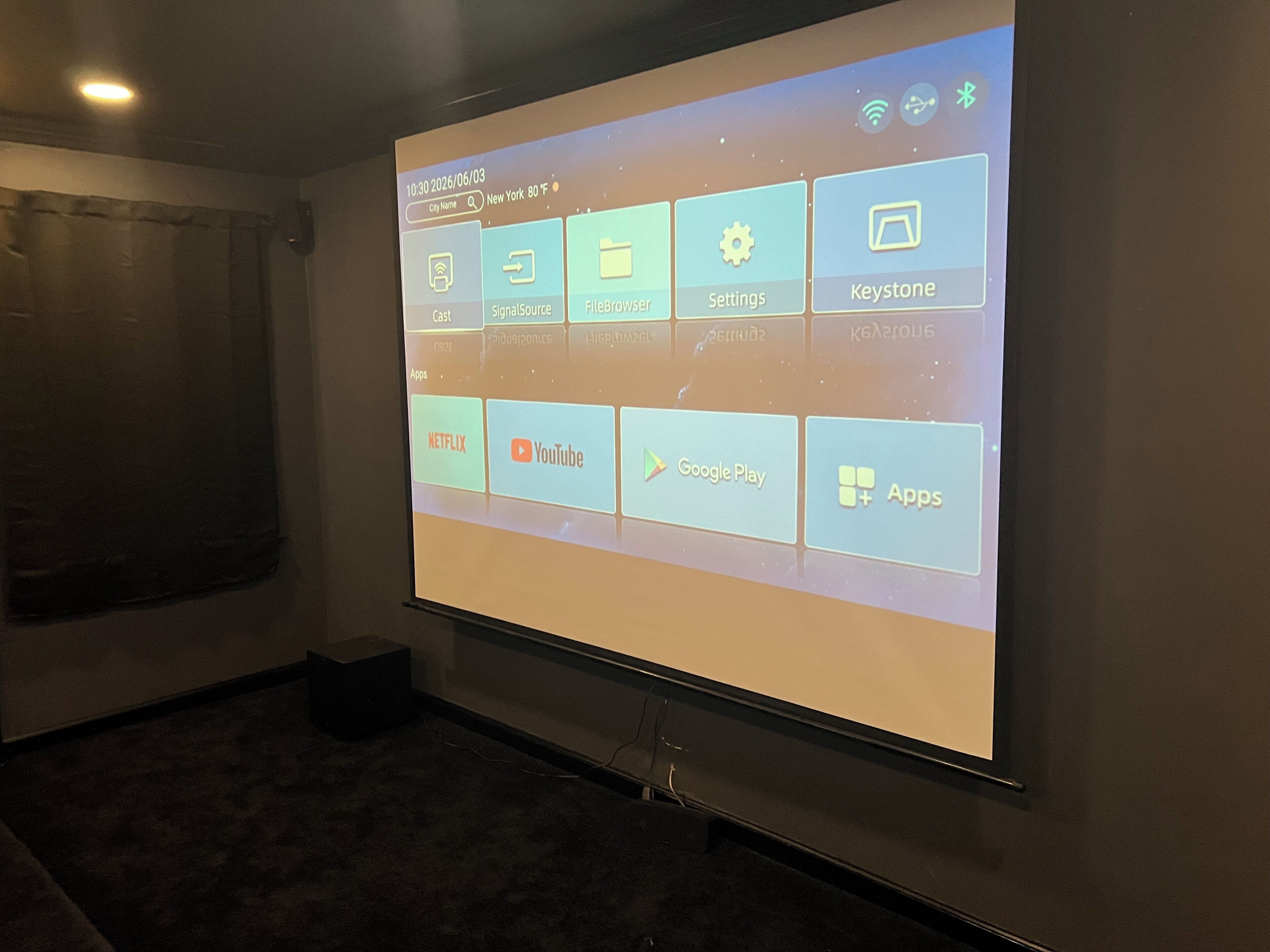 A projection screen displaying a user interface with app icons for Netflix, YouTube, Google Play, and an 'Apps' menu.