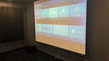 A projection screen displaying a user interface with app icons for Netflix, YouTube, Google Play, and an 'Apps' menu.