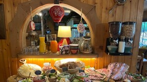 Buffet com diversos alimentos e acompanhamentos, um espelho e uma decoração pendente.