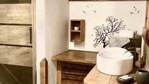 Casa de banho moderna com chuveiro de vidro, toucador de madeira e prateleira fixada na parede.