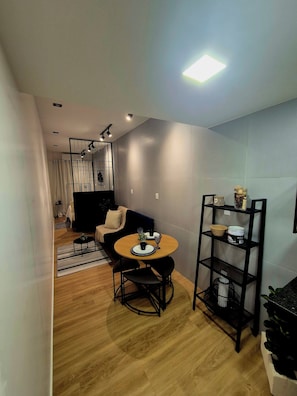 A modern living space with a dining area, a sofa, a coffee table, and a bookshelf. - Cozy studio in downtown Florianópolis. Close to everything the island has to offer. (Florianópolis)