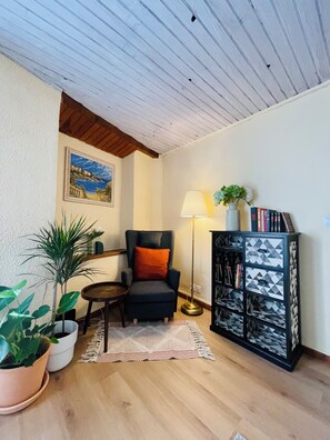 A room with a wooden ceiling, a chair, a floor lamp, a bookshelf, and potted plants. - A 3-story, 110-square-meter house from the 17th century at the foot of the Cité de Carcassonne (Carcassonne)
