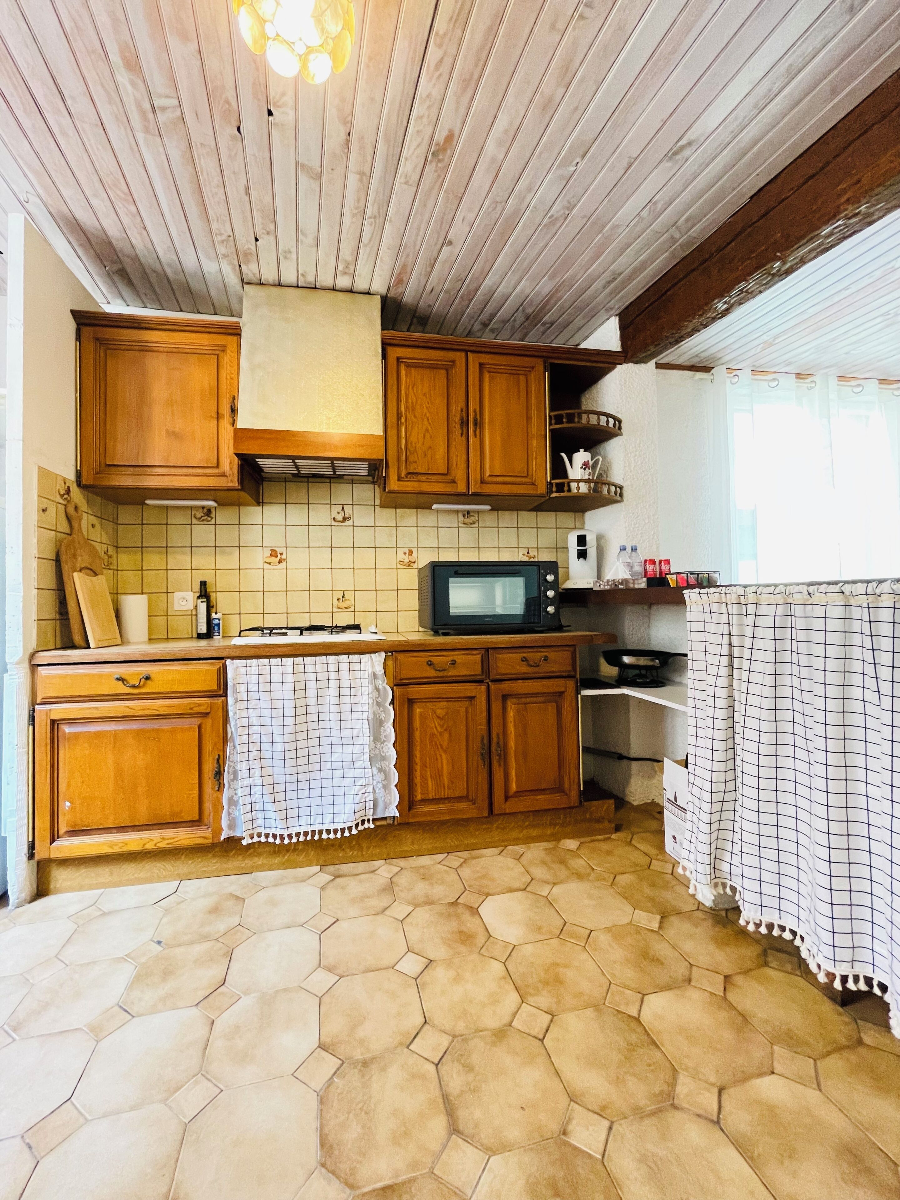 Una cucina con mobili in legno, un forno a microonde e uno schienale piastrellato.