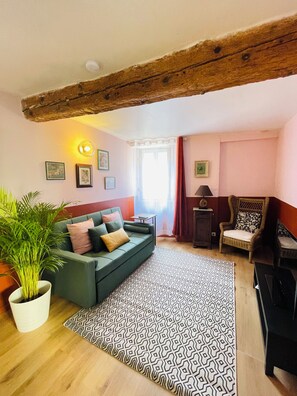 Ein gemütliches Wohnzimmer mit einem grünen Sofa, einem gemusterten Teppich und einem Holzbalken an der Decke.