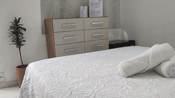 A bedroom with a bed, a dresser, a potted plant, and a curtain. - Gaivotas do Mar Búzios (Buzios)