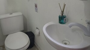 A small bathroom with a toilet, sink, and window. - Gaivotas do Mar Búzios (Buzios)