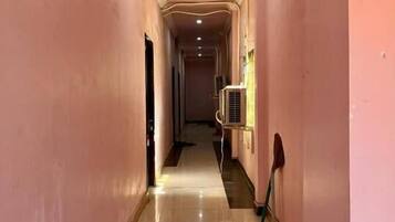 A long, narrow hallway with pink walls and a shiny floor, leading to a door at the end.