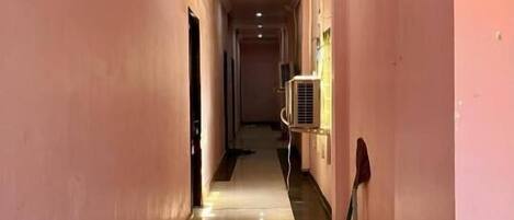 A long, narrow hallway with pink walls and a shiny floor, leading to a door at the end.