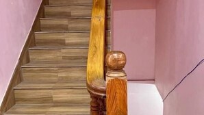 A wooden staircase with a balustrade, pink walls, and a white landing area. - Arecrata (Phnom Penh)