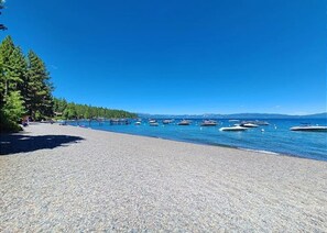 A pebble beach with boats in the water and trees in the background. - Dancing Cubs Cabin!  Hot Tub, Walk to Beach! (Homewood)