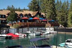 A marina with boats docked, a wooden building with multiple windows, and outdoor seating with umbrellas. - Dancing Cubs Cabin!  Hot Tub, Walk to Beach! (Homewood)