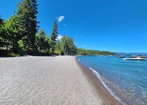 A pebble beach with clear water, boats, and trees. - Dancing Cubs Cabin!  Hot Tub, Walk to Beach! (Homewood)