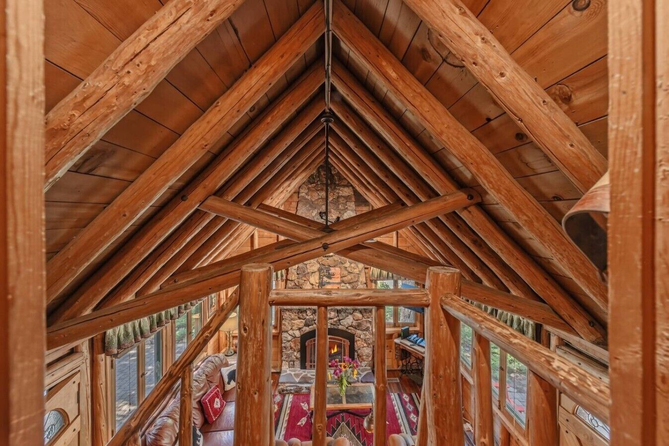 A wooden interior with a stone wall, wooden beams, and a view of the outside.
