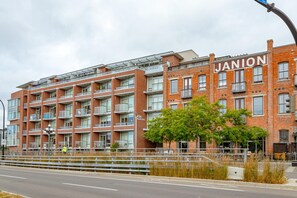 A multi-story brick building with the name 'JANION' on the facade, featuring balconies, large windows, and a pedestrian walkway. - Chic Heritage Studio in Downtown Victoria (Victoria)