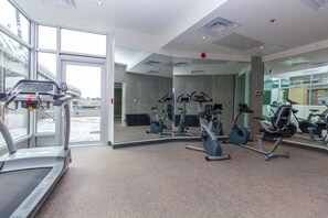 Ein Fitnessraum mit Cardiogeräten, Spiegeln und einem großen Fenster.