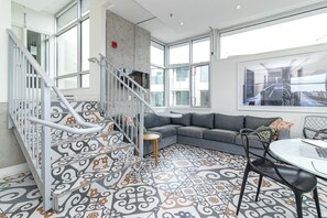 Ein modernes Interieur mit Treppe, einem grauen Sofa und fliesenbesetztem Boden.