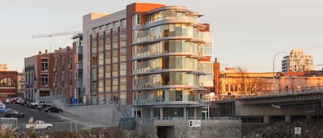 A multi-story building with a modern architectural design, featuring a mix of glass and brick facades, and a waterfront location.