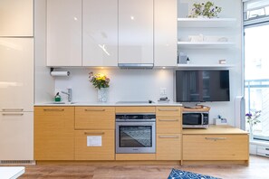 Eine moderne Küche mit Backofen, Mikrowelle und einem großen Flachbildfernseher.