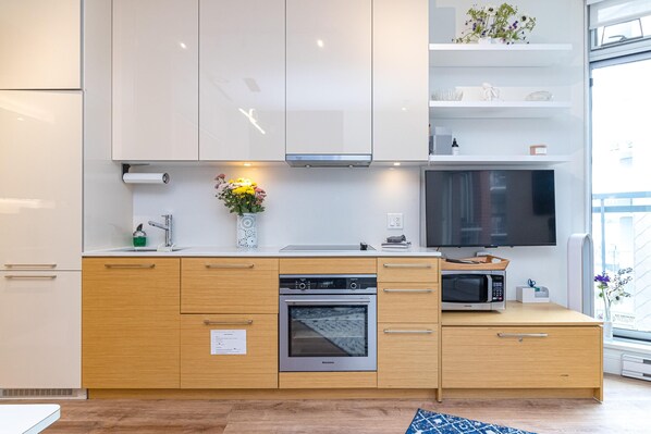 Eine moderne Küche mit Backofen, Mikrowelle und einem großen Flachbildfernseher.
