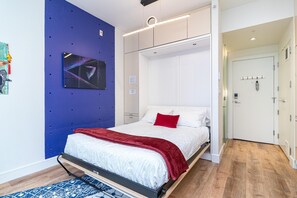 Ein modernes Schlafzimmer mit einem Bett, einer roten Tagesdecke, einer blauen Akzentwand und einem weißen Kleiderschrank.