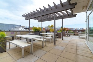 Eine Terrassenanlage mit Tischen, Stühlen, einer Pergola und Blick auf die Stadt.