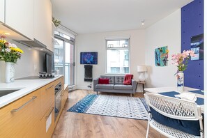 Eine moderne Küche mit Einbauherd, ein graues Sofa und ein Teppich mit blauem Muster.