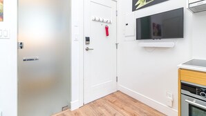 Quarto com porta branca, televisão montada, cabide vermelho e forno embutido.