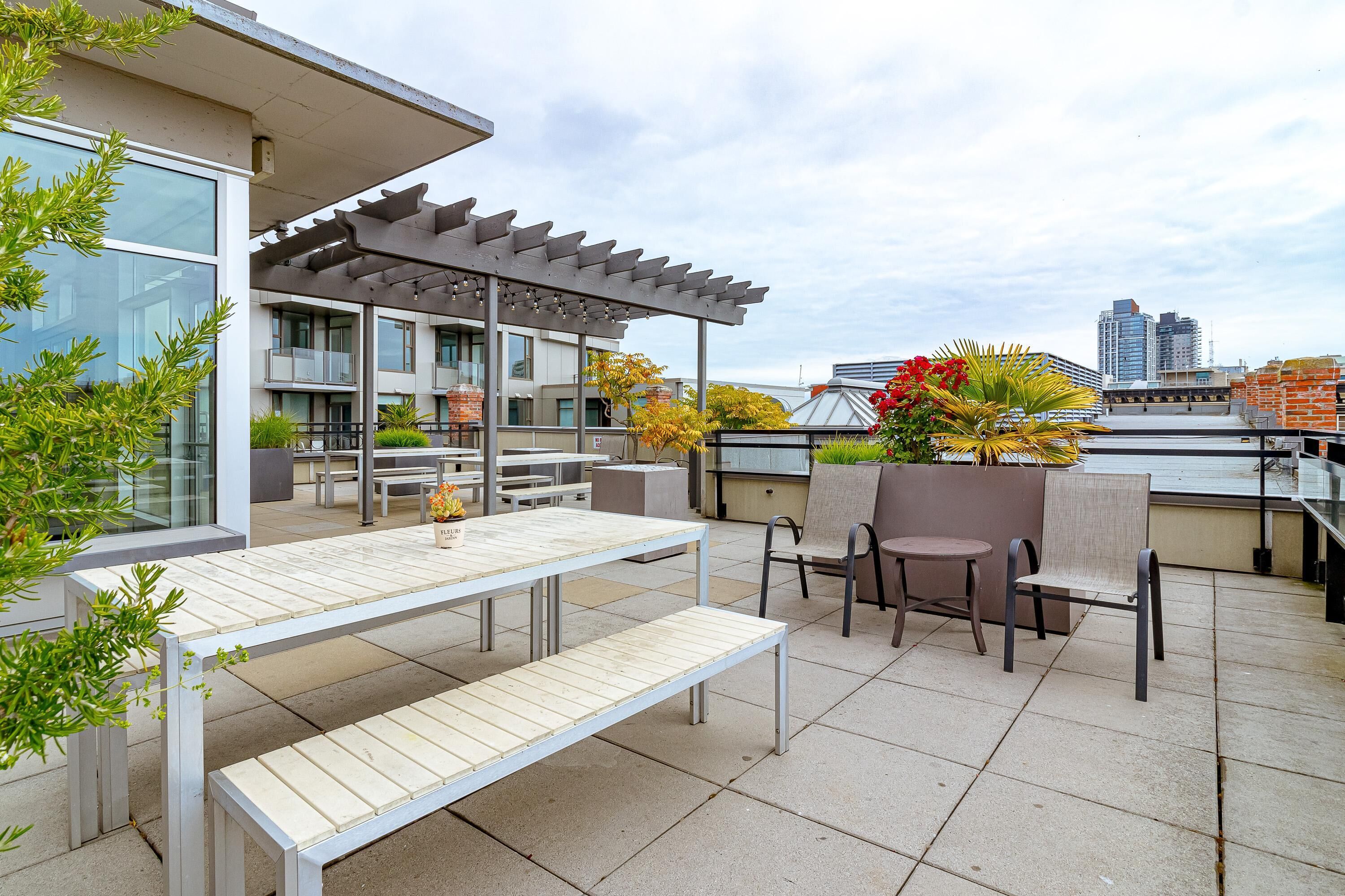 An outdoor patio with a pergola, seating, and a view of the city skyline.