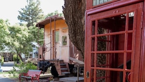 A vintage telephone booth and a train carriage in a garden setting. - London Calling Railroad Caboose Cabin (Upper Lake)