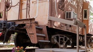 A vintage Southern Pacific train car with a platform and chain mechanism, surrounded by greenery.