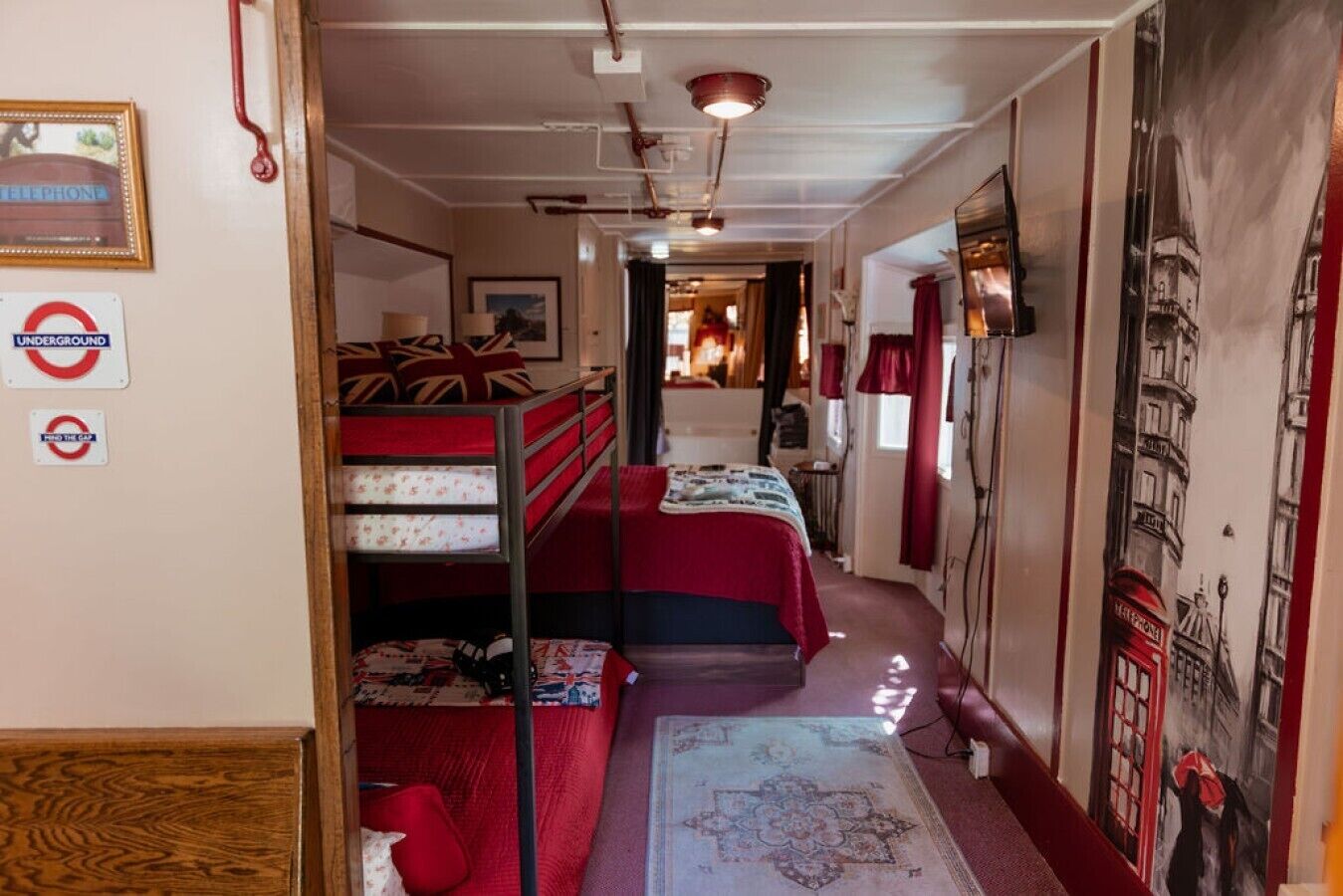 A narrow corridor leading to a room with bunk beds, a bed, and a wall with a map.