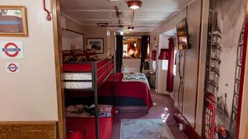 A narrow corridor leading to a room with bunk beds, a bed, and a wall with a map.