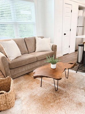 Ein Wohnzimmer mit einem braunen Sofa, einem Holztisch und einem flauschigen Teppich.