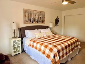 A bedroom with a bed, a nightstand, a wall-mounted lamp, a ceiling fan, and a painting. - Best Pinetop Lakes Country Club Spot ~ Newly Done (Pinetop Country Club)