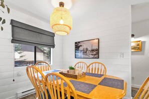A dining area with a table, chairs, a hanging light fixture, and a window with a view. - Best Pinetop Lakes Country Club Spot ~ Newly Done (Pinetop Country Club)