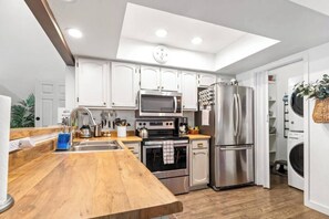 A modern kitchen with white cabinets, stainless steel appliances, a wooden countertop, and a built-in oven. - Best Pinetop Lakes Country Club Spot ~ Newly Done (Pinetop Country Club)