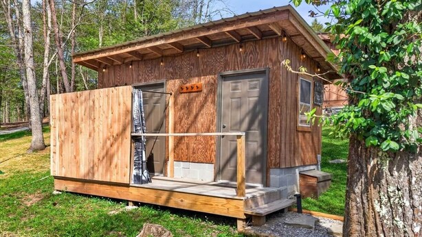 Una cabaña de madera con un porche, una puerta y una ventana.
