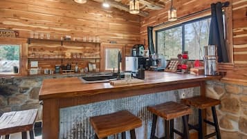 A rustic wooden interior with a bar area, stone walls, and a large window.