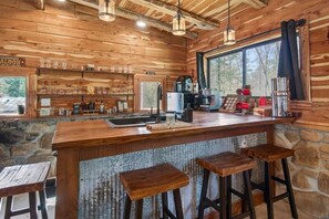 A rustic wooden interior with a bar area, stone walls, and a large window.