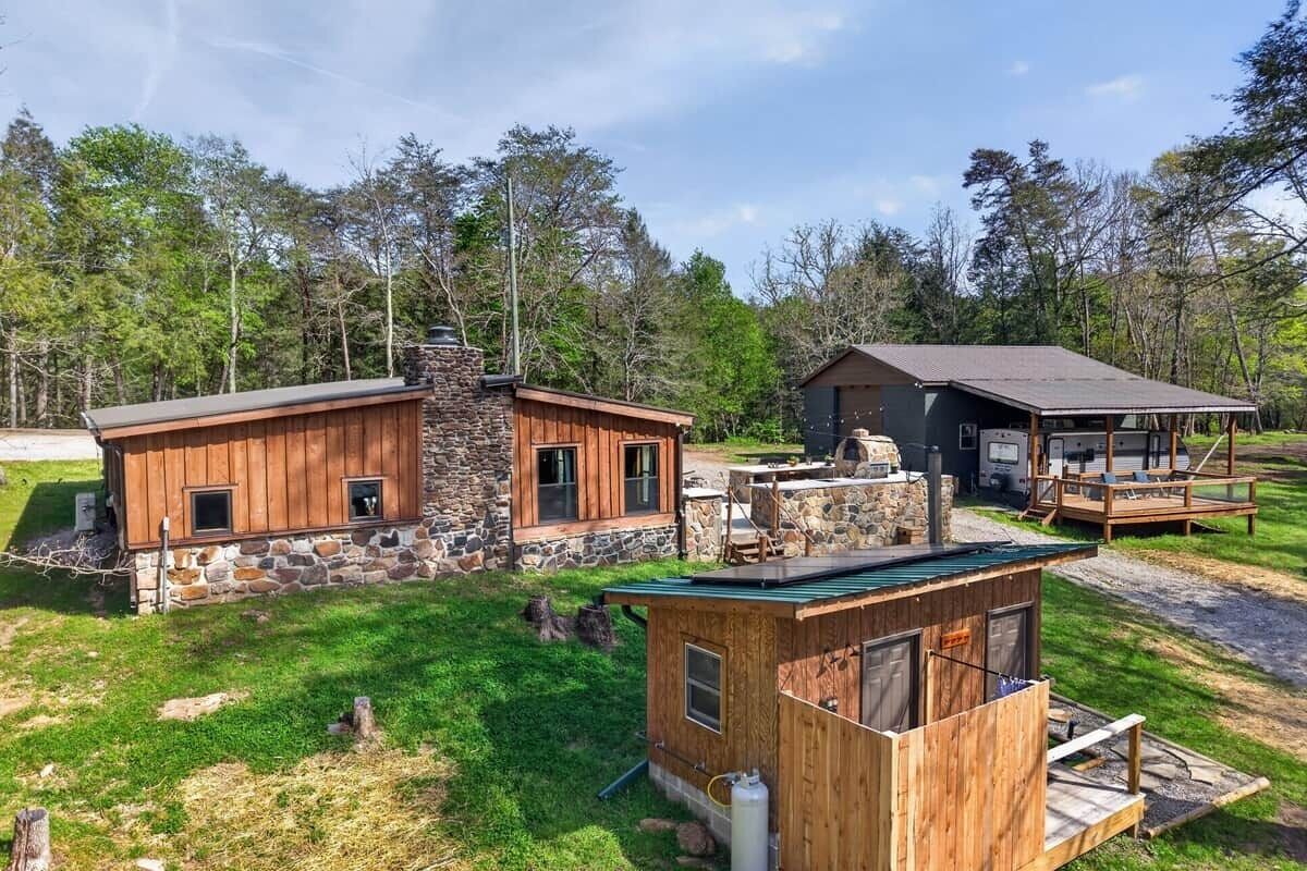 A cabin with a stone exterior, a wooden deck, and a separate wooden structure.