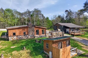A cabin with a stone exterior, a wooden deck, and a separate wooden structure. - Stagecoach Saloon Riverside cabin with stone pizza oven (Cumberland County)