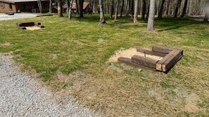 Zona arbolada con una construcción de madera, un sendero de grava y un campo cubierto de césped.