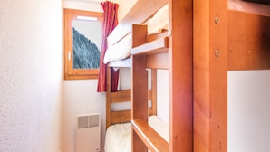 A bunk bed room with a window, a heater, and a view of a forest. - Family Apartment 60 m From Ski-slope (Modane)