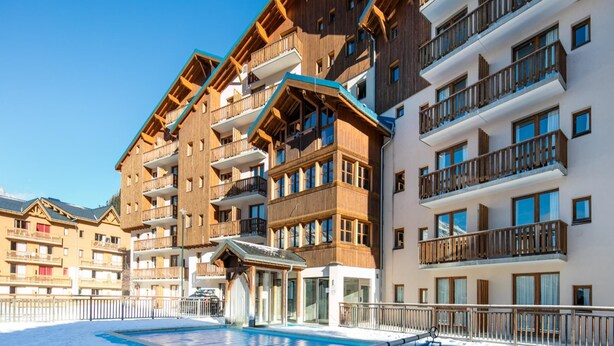 A multi-story hotel with balconies, a pool area, and a ski lift visible in the background. - Family Apartment 60 m From Ski-slope (Modane)
