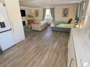 A compact room with a bed, a sofa, a dining table, and a kitchenette. - Annexe @ Meadows Farm (Swansea)