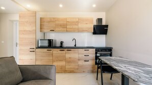 Eine moderne Küche mit Holzschränken, einer eingebauten Mikrowelle und einem Essbereich mit einem Marmortisch.