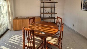 A dining area with a wooden table and chairs, a pendant light, a built-in shelf, and a window with curtains. - Apartment with ocean views, a 10-minute walk from the waterfront (Roses)
