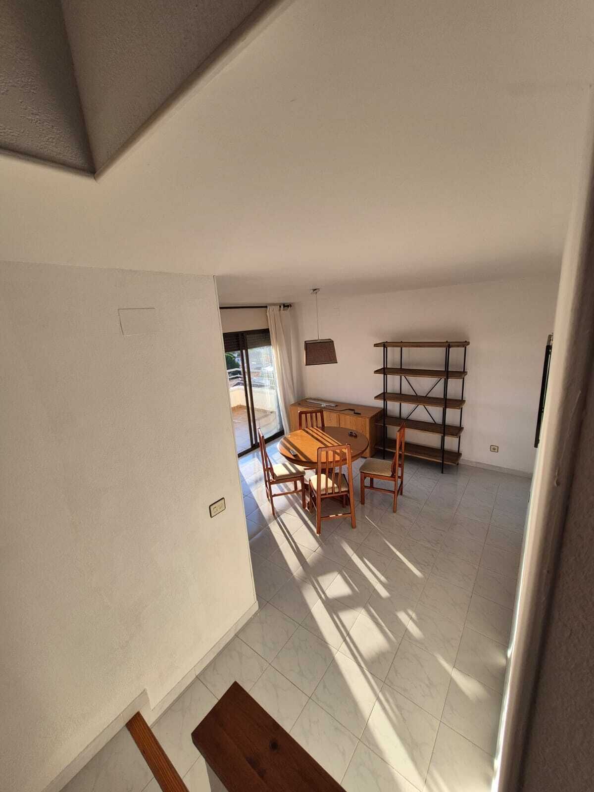 A spacious room with a dining table and chairs, a wooden bench, and a shelving unit.
